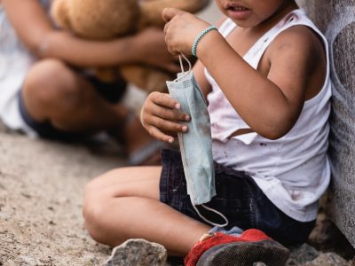 cropped view of poor african american kid holding dirty medical mask near sister